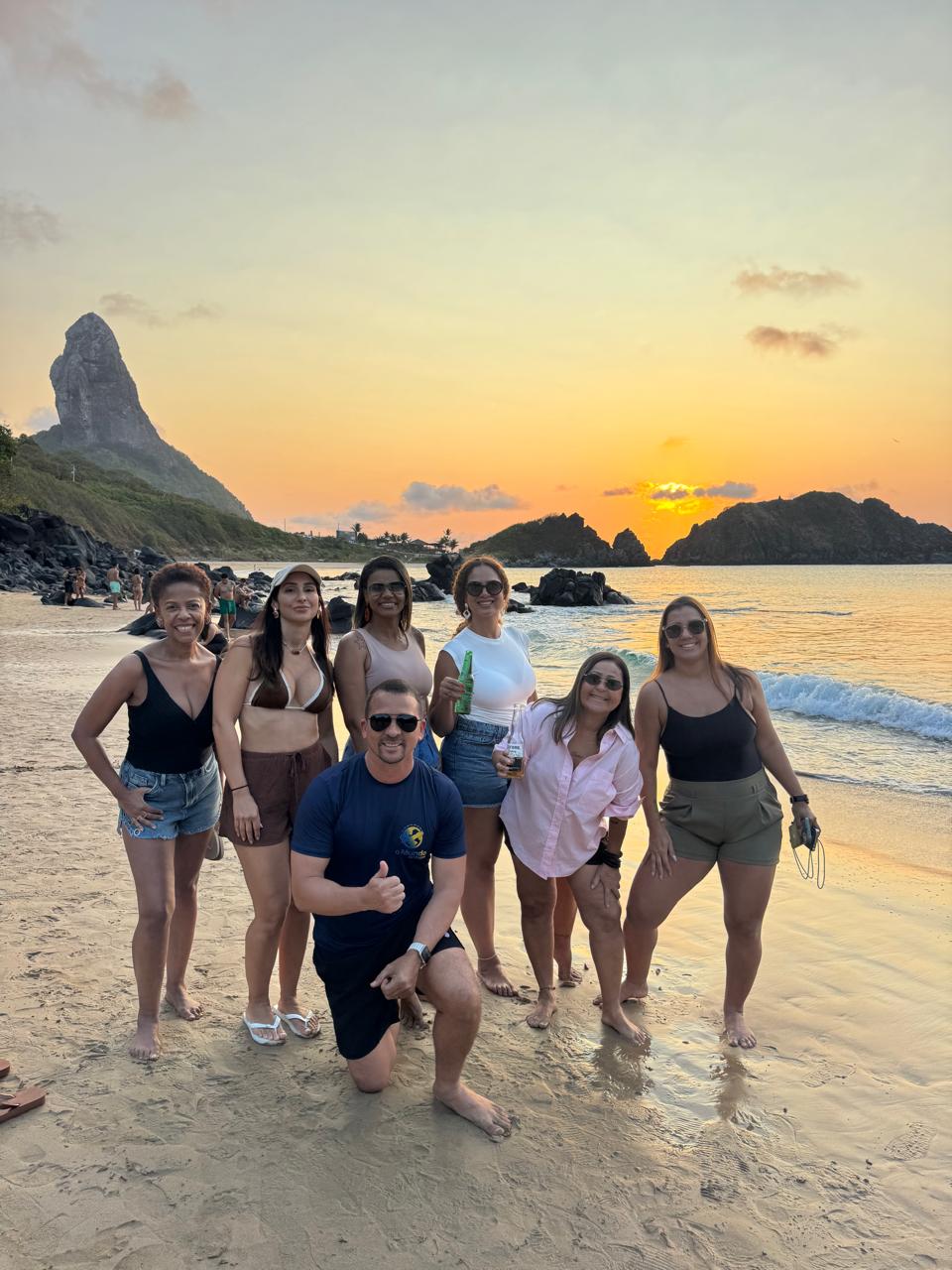Grupo reunido na praia ao pôr do sol